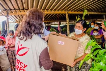A prosper global member hands a box of aid items to a person in alta verapaz in guatemala. 