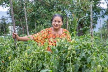Guatemalan women stands smiling in a field.