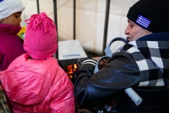Khalid shares the space heater in one of prosper global's shelters with two young girls so they can all warm up from the cold.