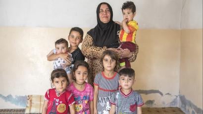 Faiza (center) with her grandchildren and nephews. Faiza’s home was destroyed and her car burned. There is nothing left there, she says. Emergency cash has helped Faiza ensure her family's needs are met in the temporary home they share with five other groups.