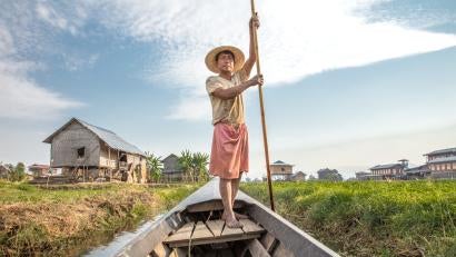 Man guides boat through waterway.