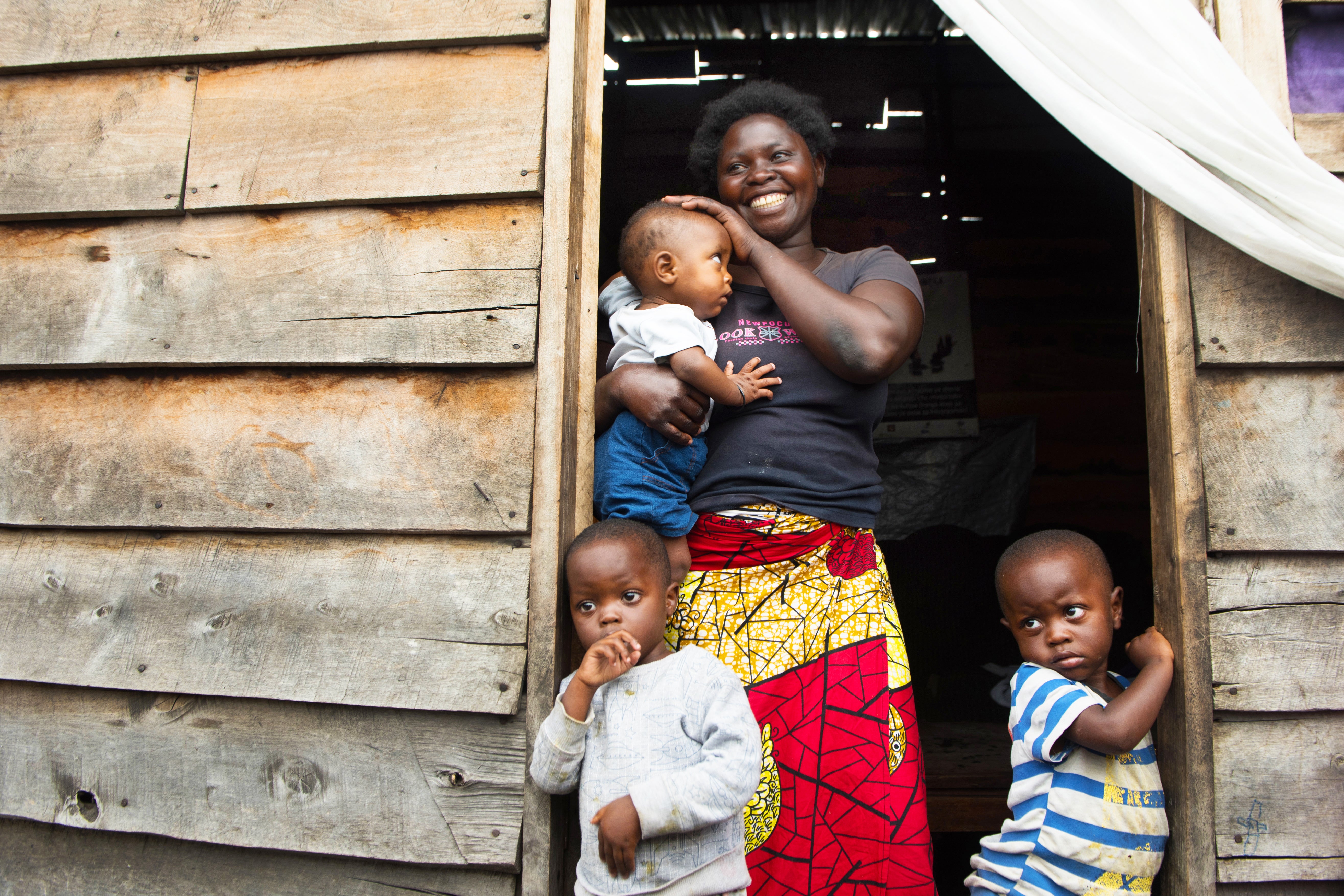 Justine stands in the doorway of her small wooden home, which is the only source of light for the tiny space built on lava rock. She and her family are grateful for the Prosper Global tap stand across the street that brings clean water close to their home. Photo: Liz Hummer/Prosper Global