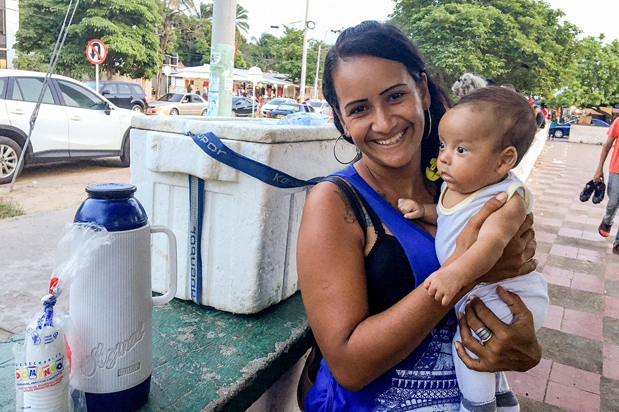 Elisa, a Venezuelan migrant to Colombia sells water and coffee in a park with her newborn child. Photo: Ana Maria Olarte/Prosper Global
