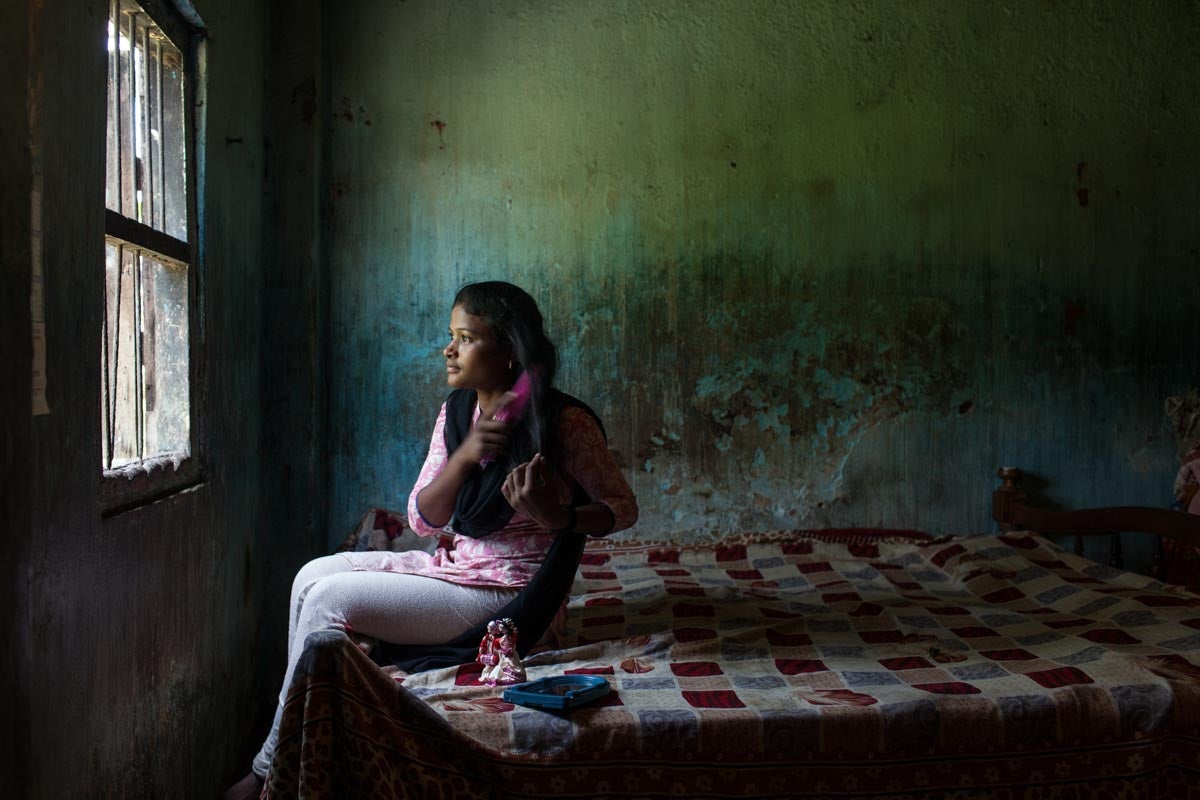 Teen girl in India sitting on her bed and brushing her hair