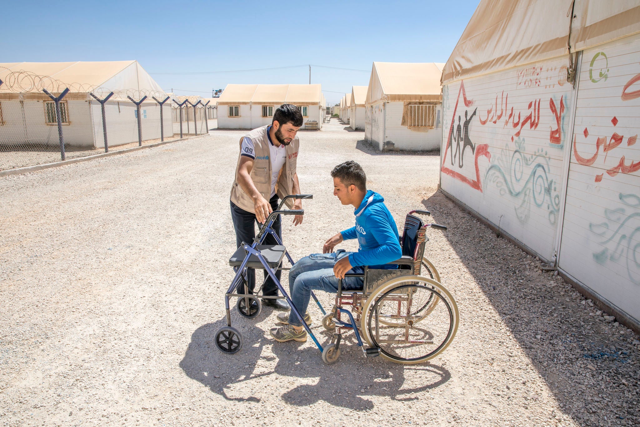 A Prosper Global team member works with a young man who uses mobility equipment at a refugee camp in Jordan