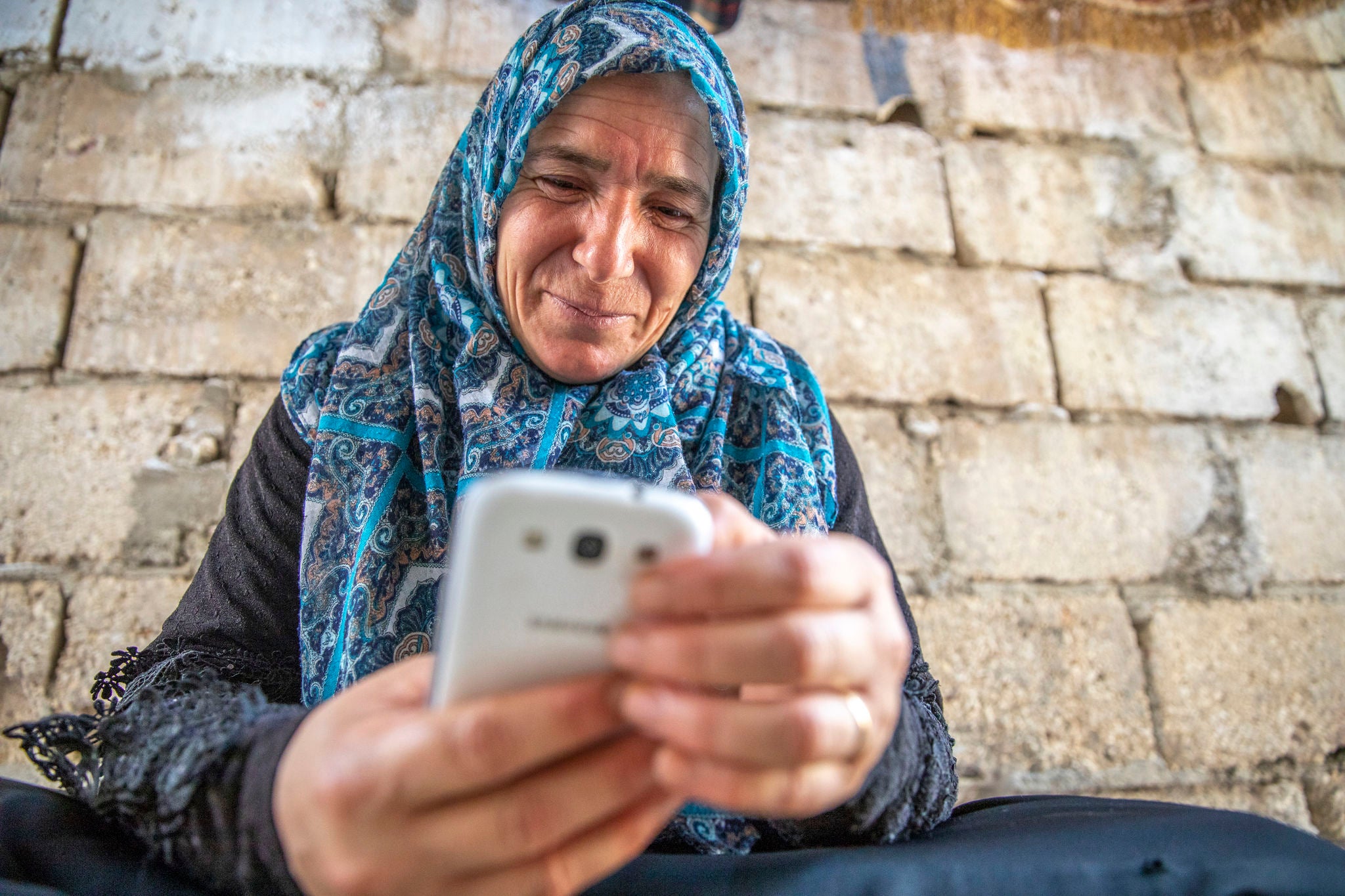 A Syrian refugee uses her mobile phone to access digital banking services in Jordan.