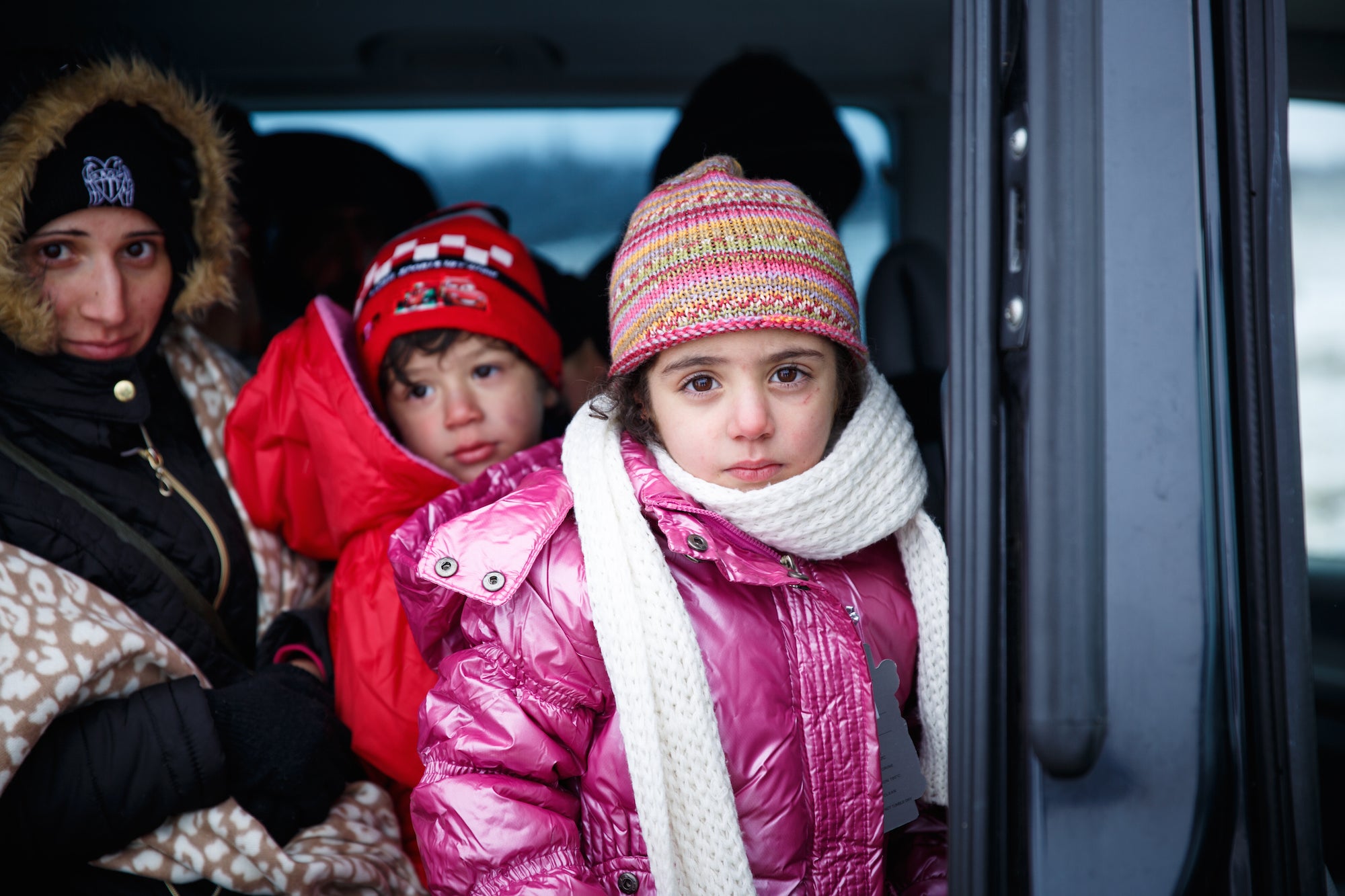 A young girl in a pink coat, hat and scarf