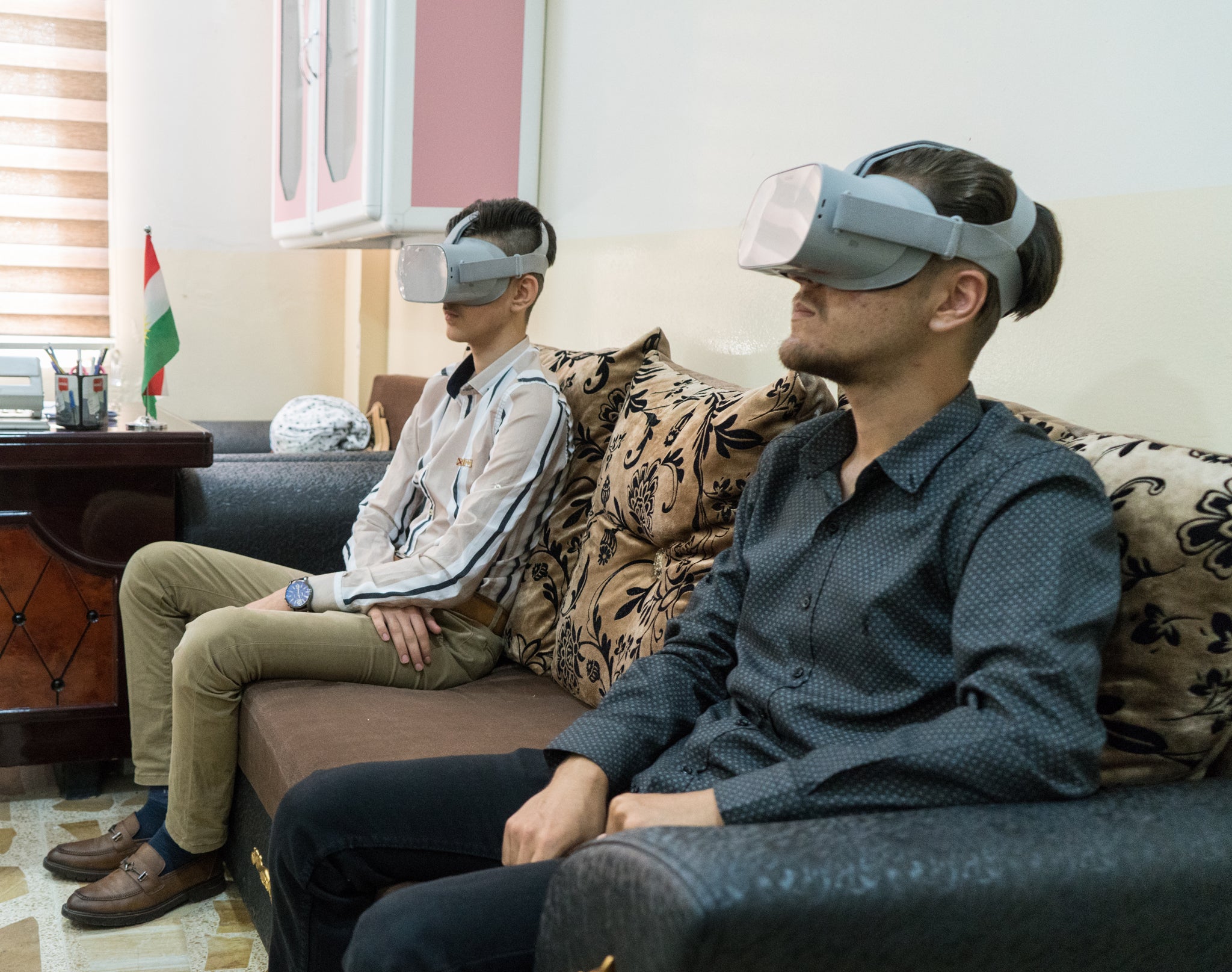 Two young participants in Iraq wear virtual reality goggles which provide visual and audial immersion.
