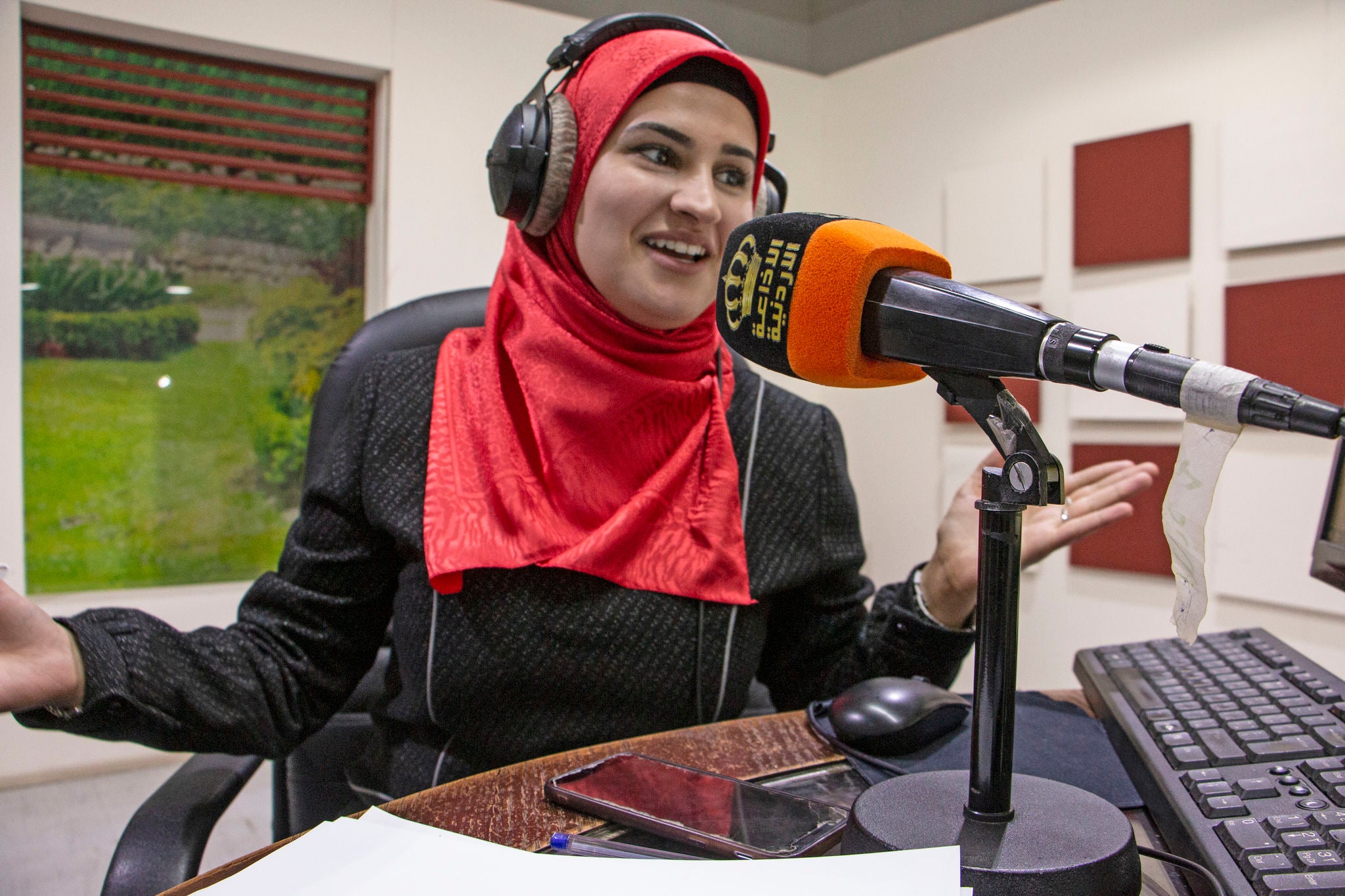 A person wearing headphones speaks into a microphone inside a broadcast studio in Jordan. 