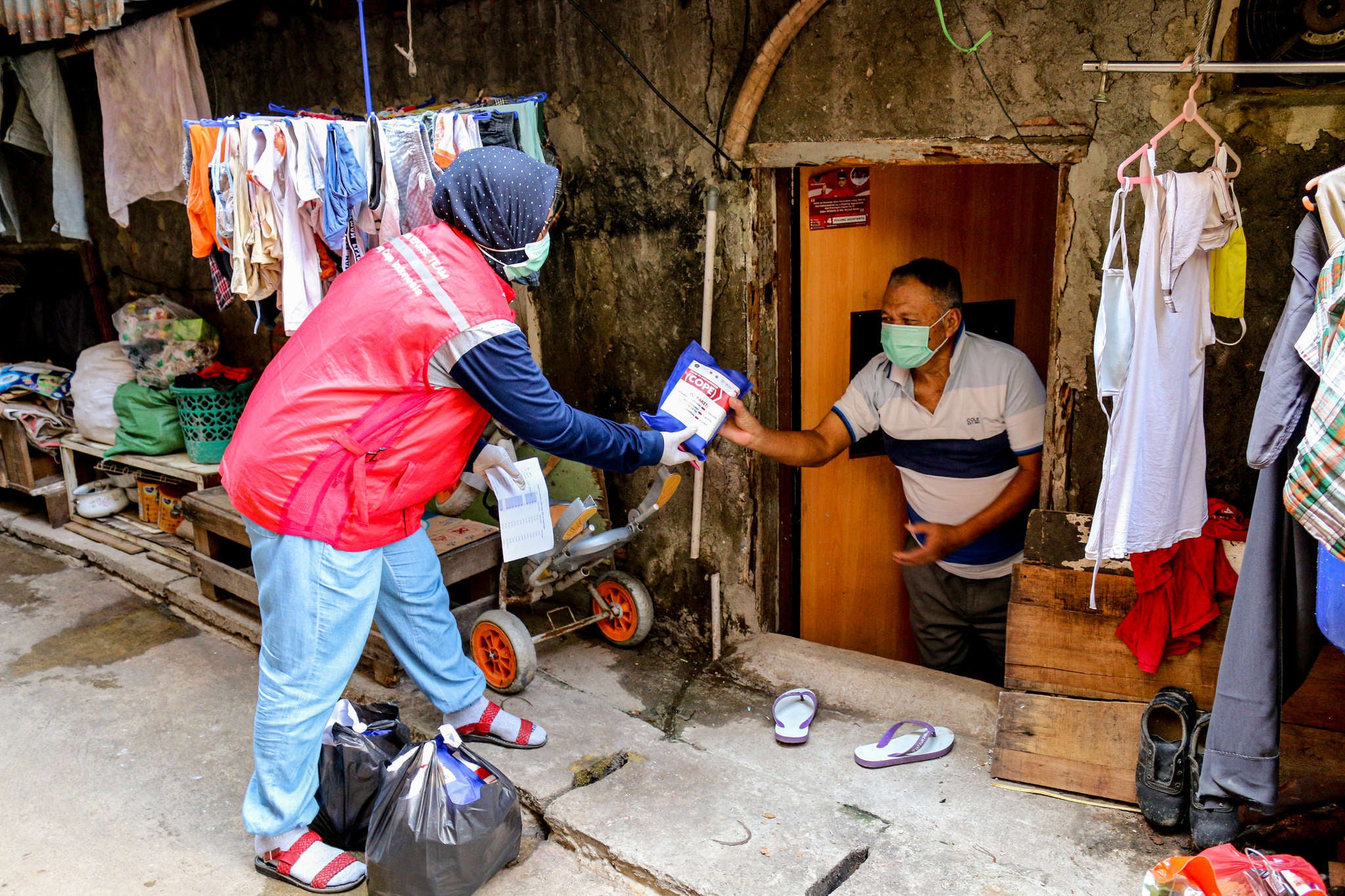 A Prosper Global staff team member hands someone a hygiene kit during a door to door community outreach event in Jakarta Province.