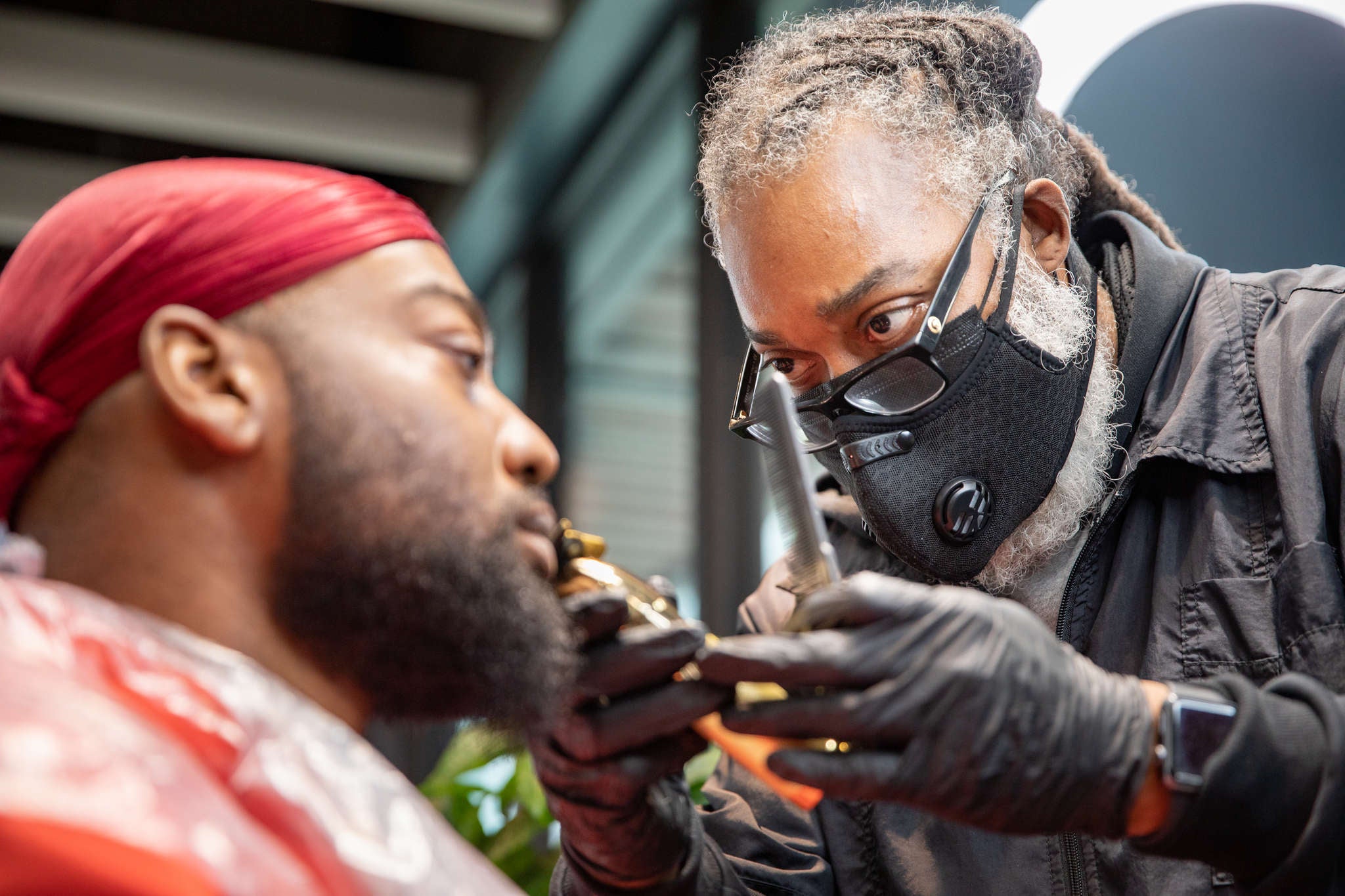 A barber trims the beard of a customer. 