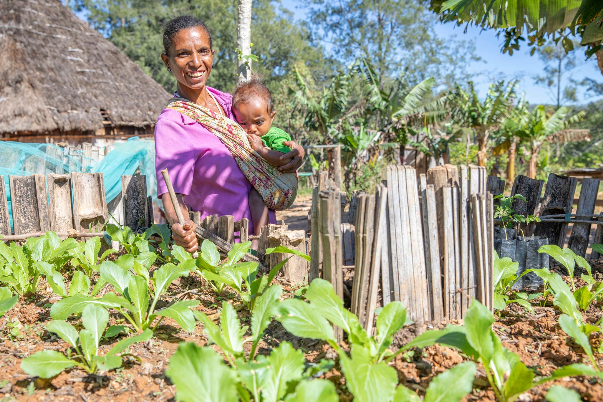 Timor Leste woman in vegetable garden with child.