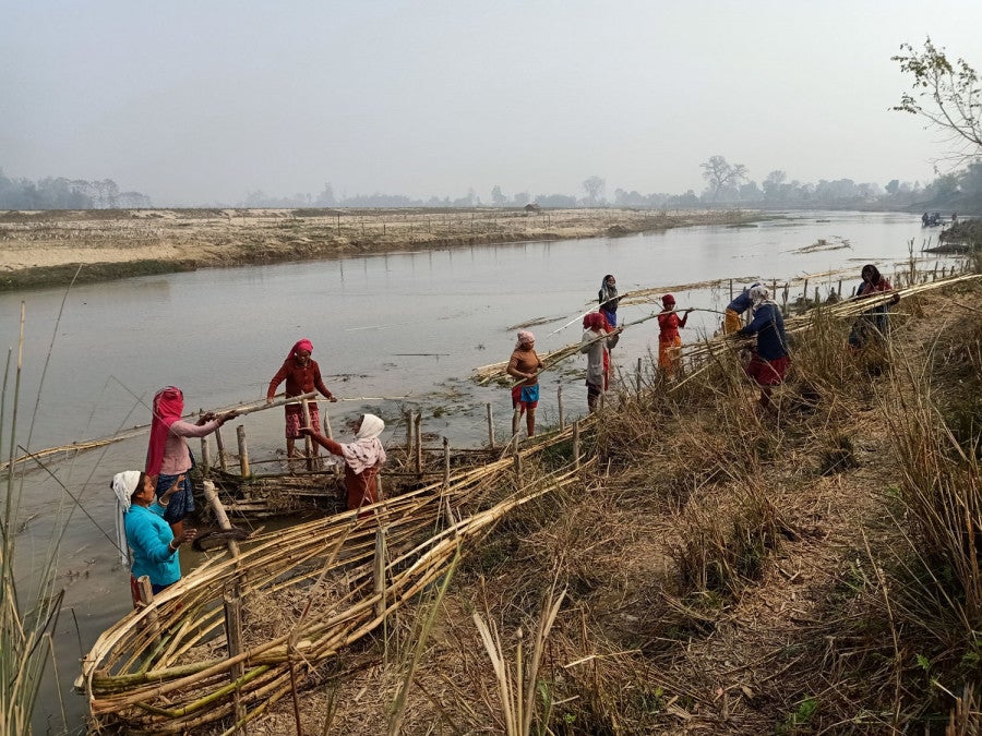 Women in Badabaika, Nepal build bamboo spurs to protect their land from floods.