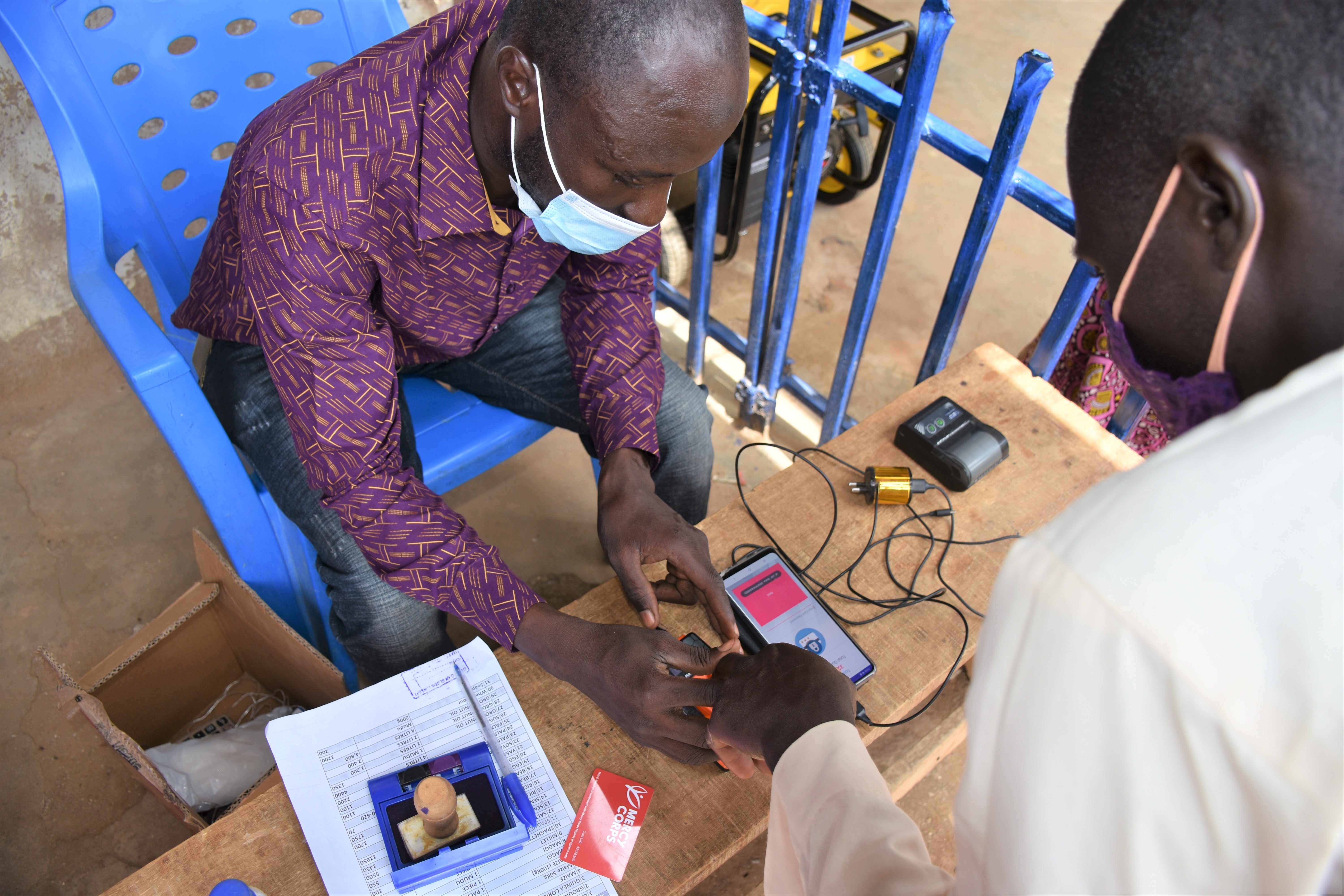 A Prosper Global team member assists an e-voucher recipient with a digital identity process, increasing security and efficiency.