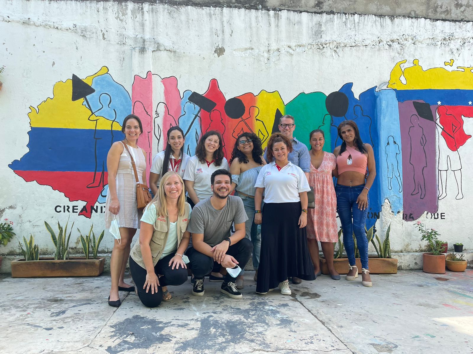 Prosper Global Colombia team members and participants stand in front of a mural celebrating unity.