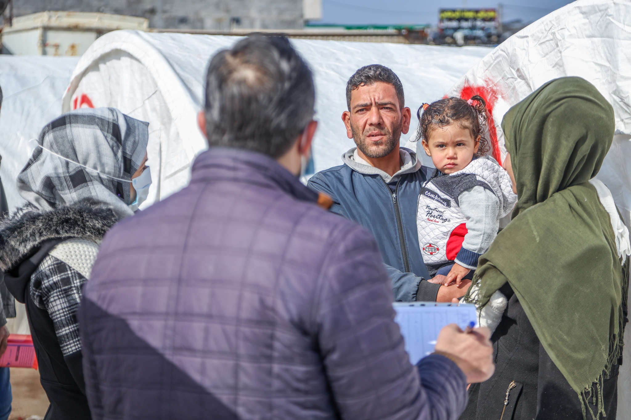Adults with children speaking with aid workers about receiving emergency supplies.
