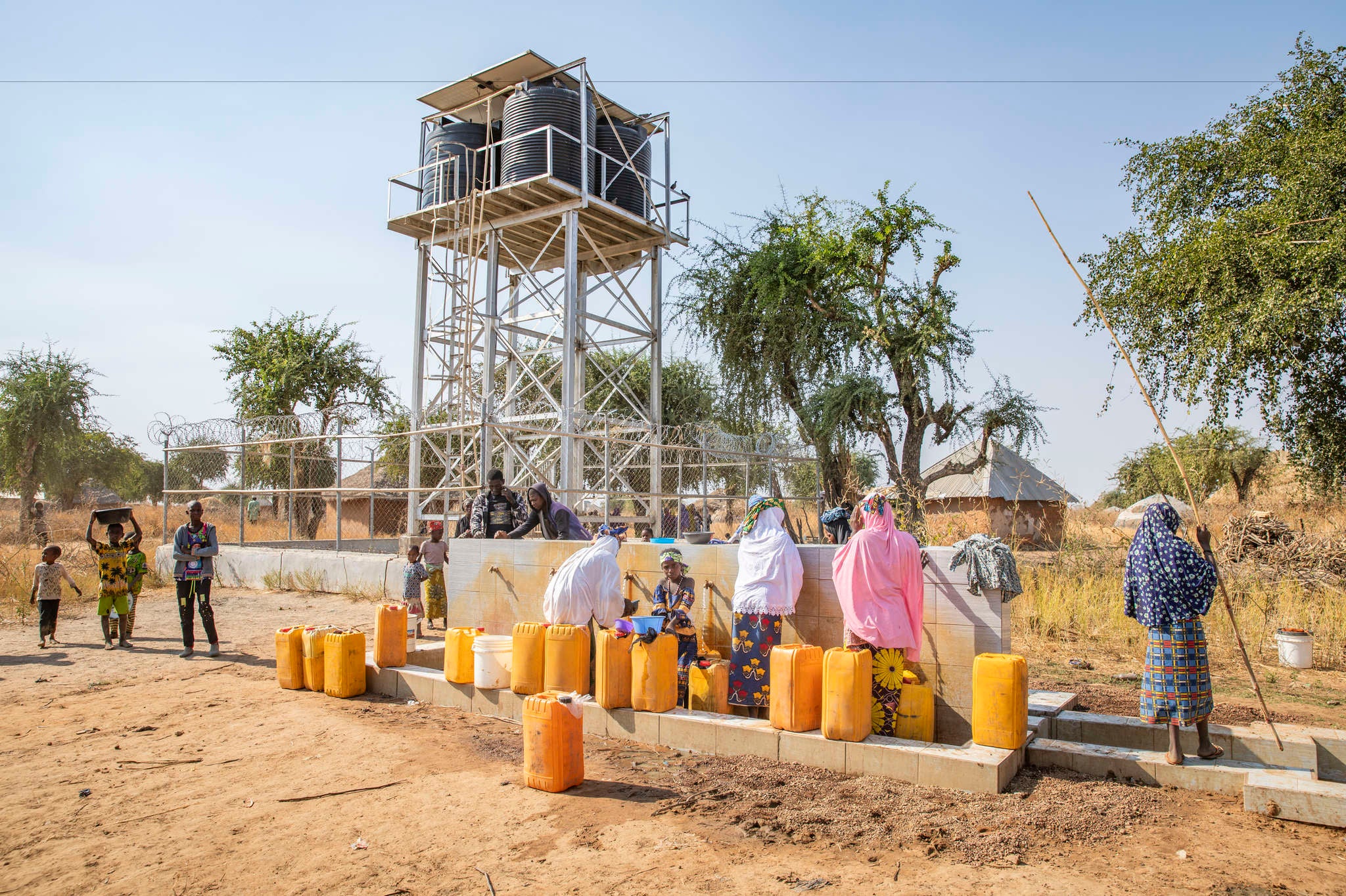 Herders and farmers fill jerrycans from a water point installed by Prosper Global.