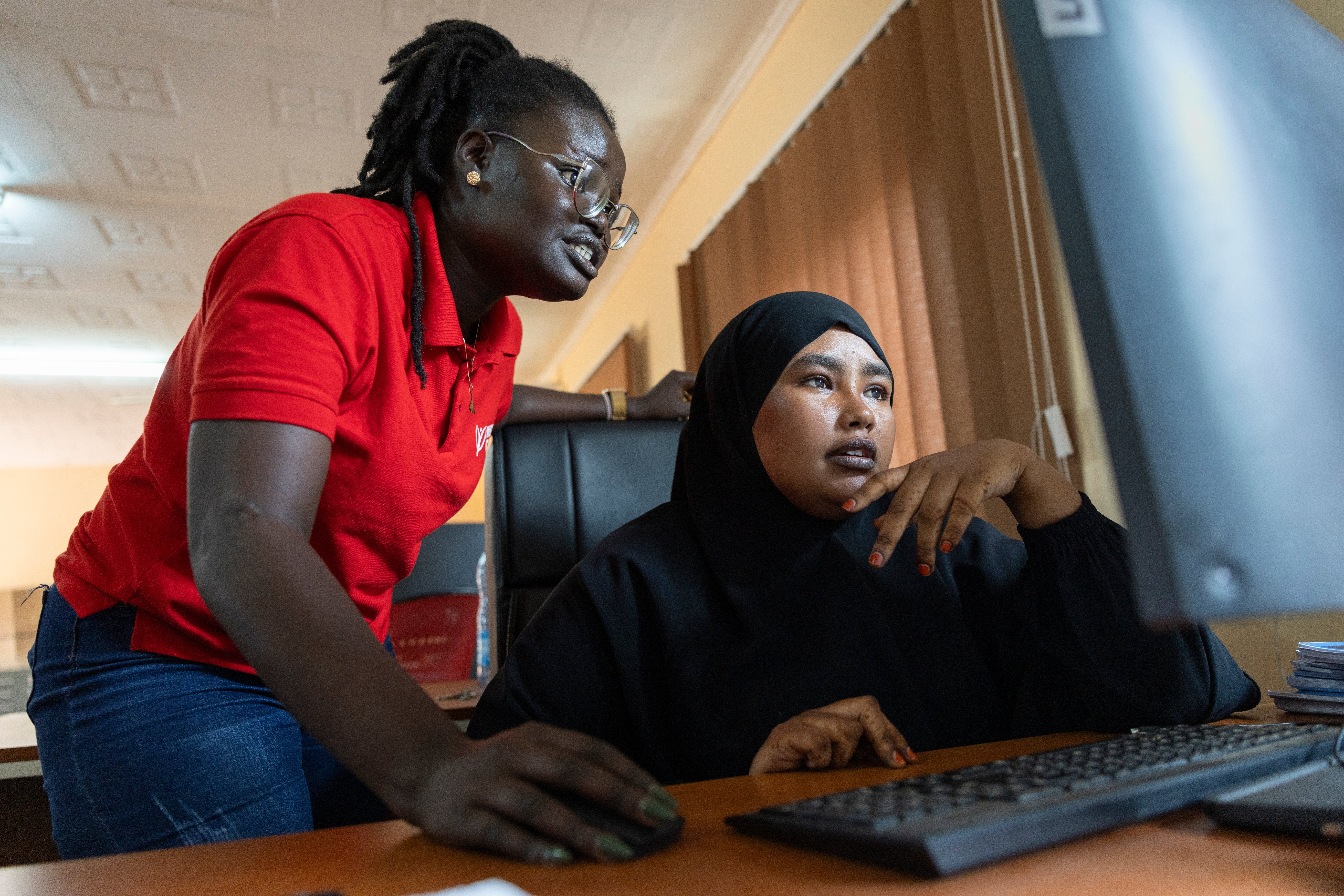 Two Kenyan women work in front of a computer together.