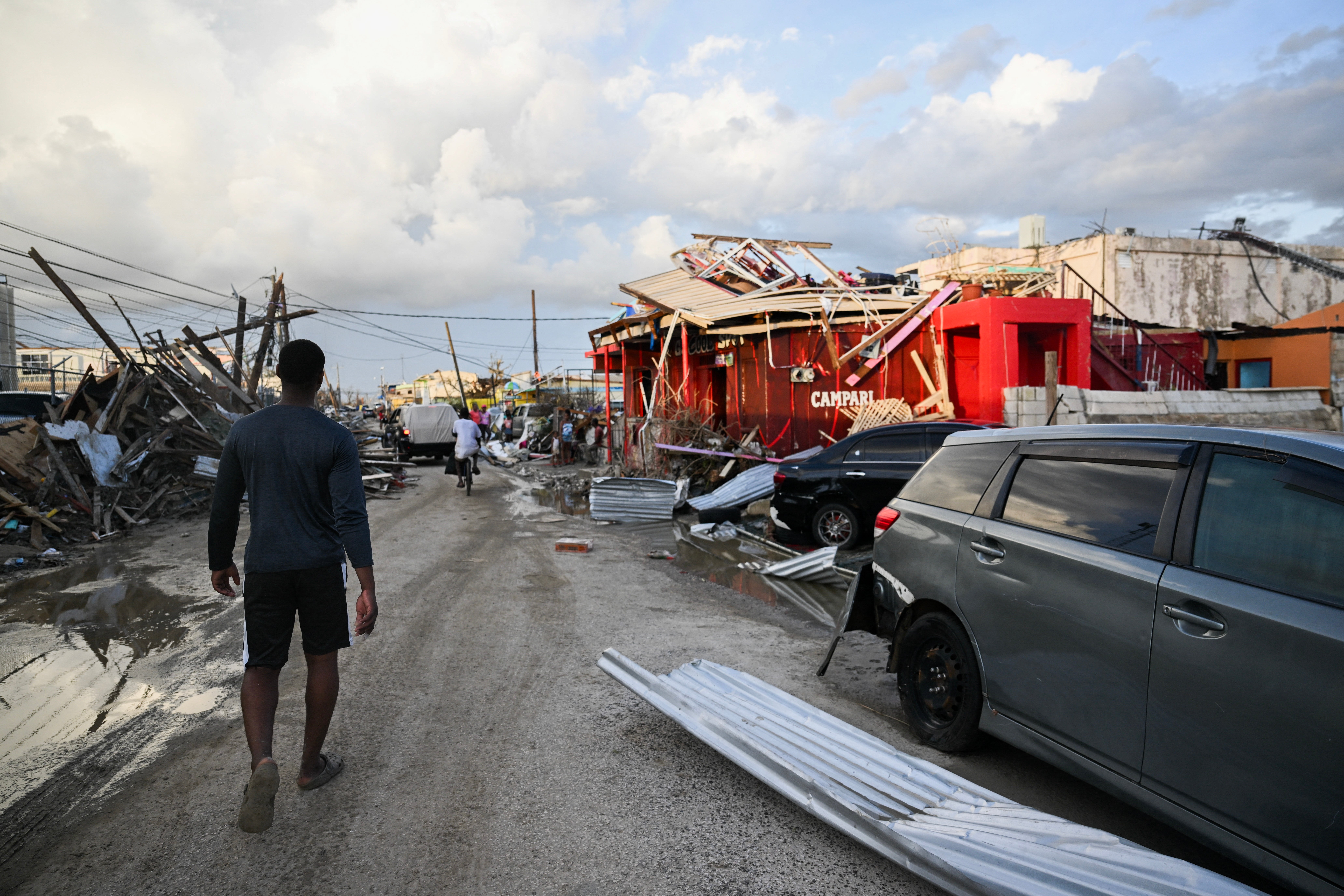 Jamaican walks through street and the Hurricane Melissa destruction.