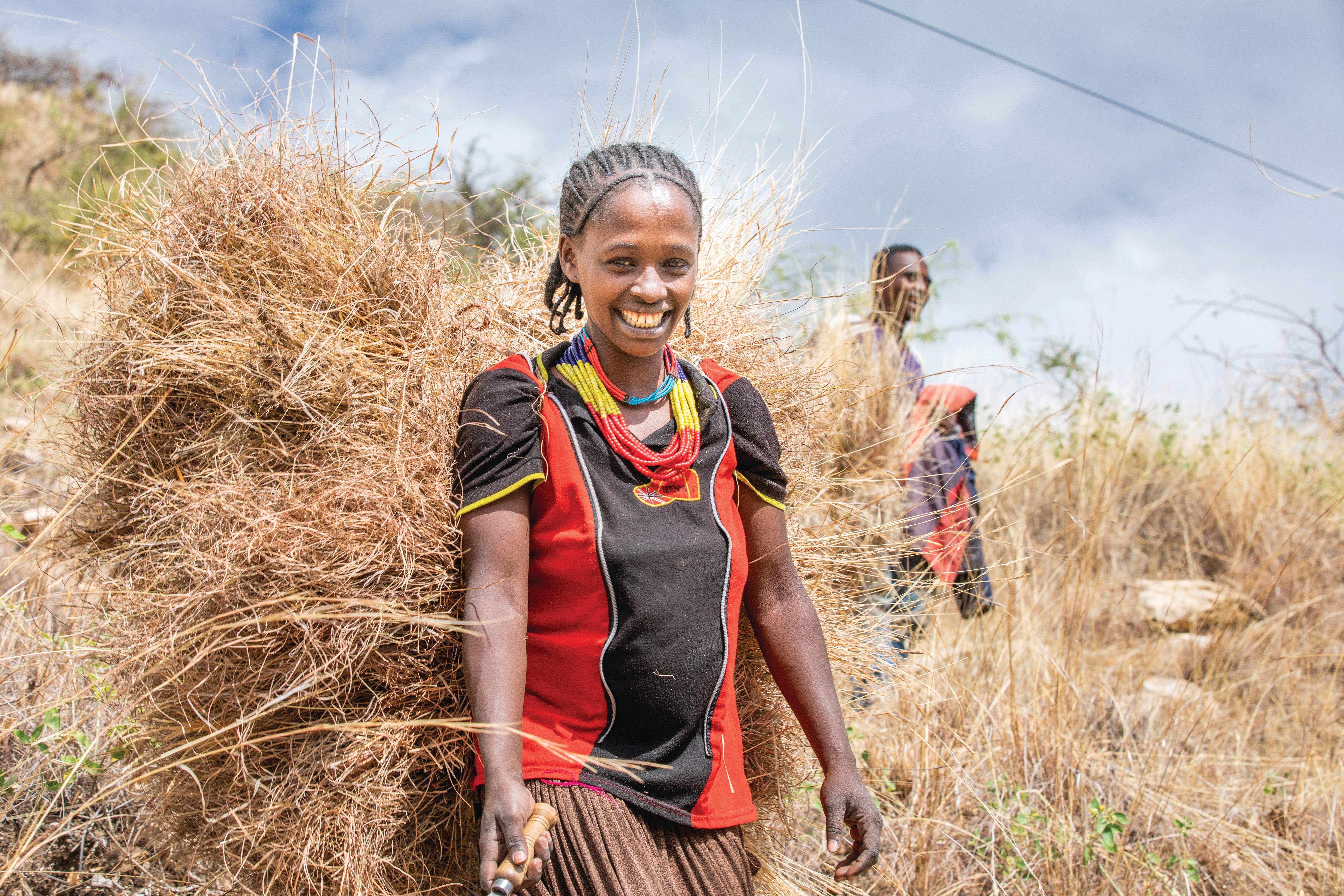 A woman with a bale of grasses on her back.