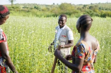 John sanya, project officer for prosper global in the yumbe district, talks with the members of unit business group in their sesame fields.
