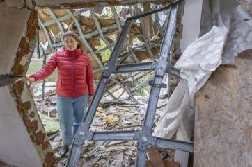 Ukrainian mother stands amidst the rubble of her home.