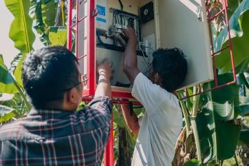Marwan (right) helps maintain the solar-powered emergency warning system.