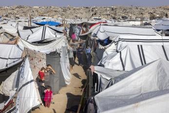 Palestinian children standing amidst a tent city.