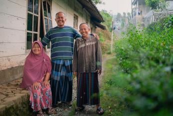 A man and his parents pose outside their home in indonesia