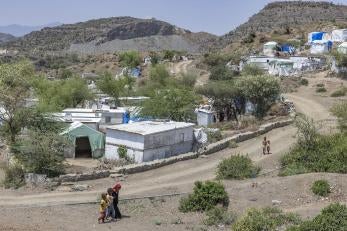 Refugees walk along a street lined with temporary shelters in yemen
