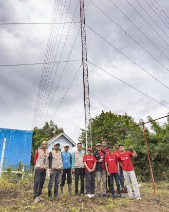 Indonesians standing in a group in front of radio antenna.