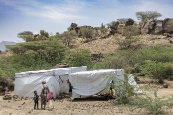 Family stands in front of makeshift shelters in Yemen.