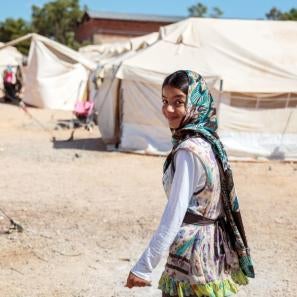 Girl in green scarf smiling at refugee camp