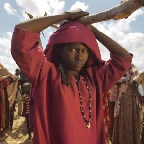 Girl holding a large stick over her head with people in the background