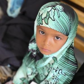 Girl next to a person holding a young child