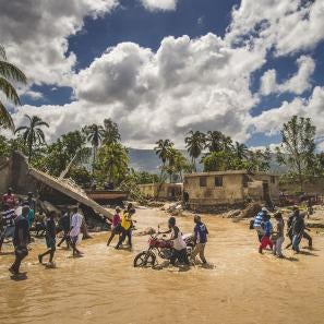 Haitians crossing flooding river in their community