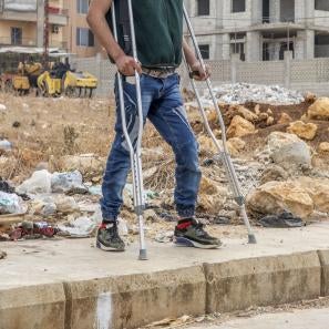 Disabled individual standing in front of empty lot.