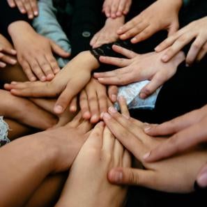 Several hands reaching to the center