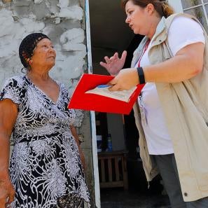 A prosper global team member holding a folder, paper and pen speaks to a woman in puerto rico