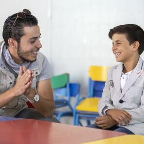 At a youth center in zaatari, omar al-tal sits with mohammad. mohammad is able to play sports and games while learning important life skills like computers and english. two of mohammad’s favorite activities are playing foosball and soccer, but his favorite is singing. at a recent talent show in the center, he finished third. photo: ezra millstein/prosper global