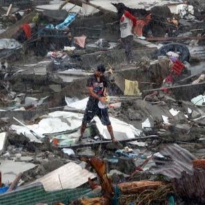 A person is pictured standing in a salvage yard in a rainstorm