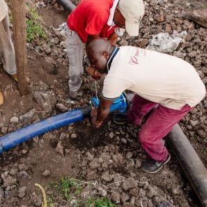 Men work to connect water pipes in dr congo