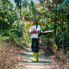 Marwan stands among cocoa trees on his farm in indonesia.
