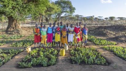 Kenyan community members standing as a group amidst agricultural crops.