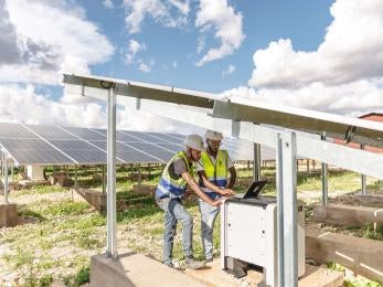 Two technicians work on a solar power plant in Sheder Refugee Camp in Ethiopia.